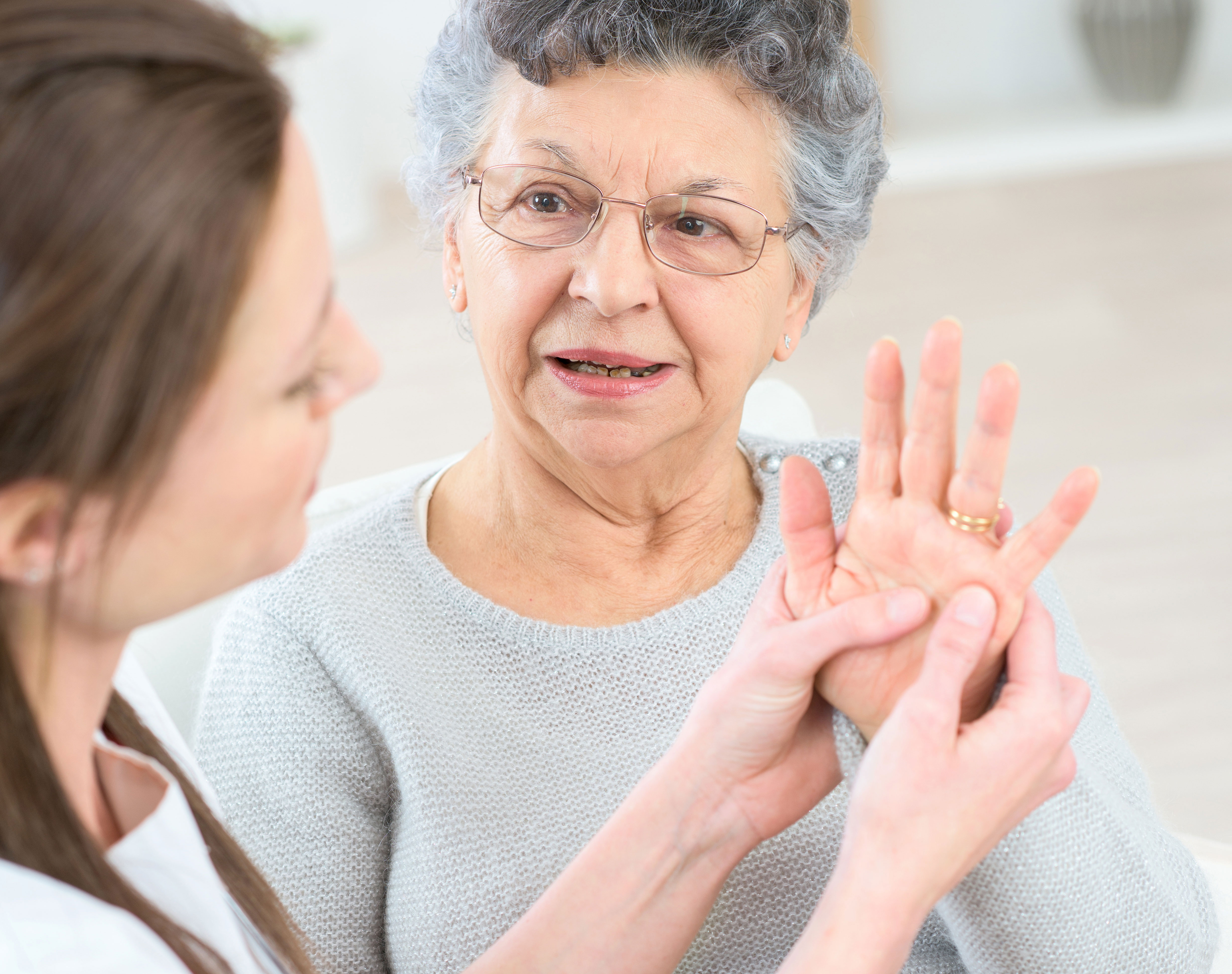 Physical therapist helping elderly woman with hand pain