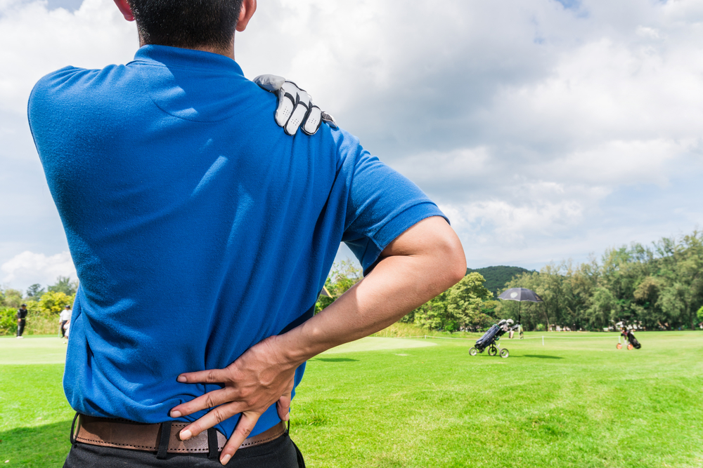 man with back pain playing golf