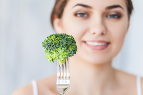 woman holding broccoli on fork