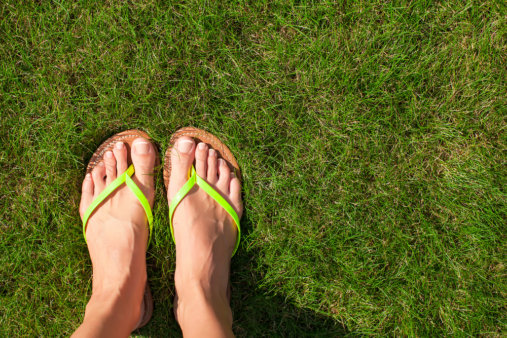 feet in flip flops on the grass