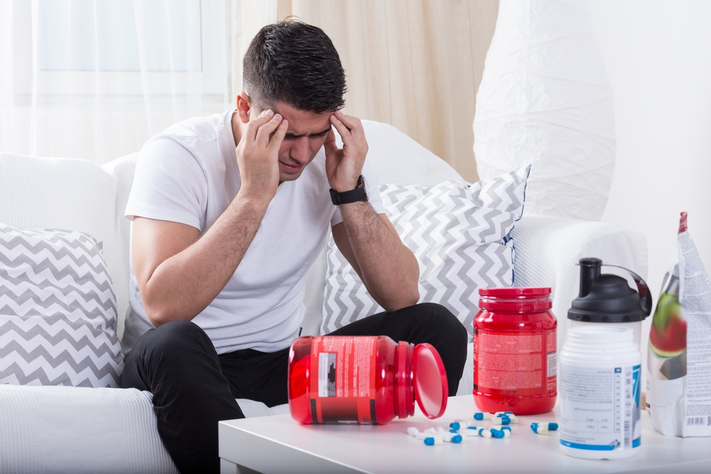 athletic man with worry and taking many supplements