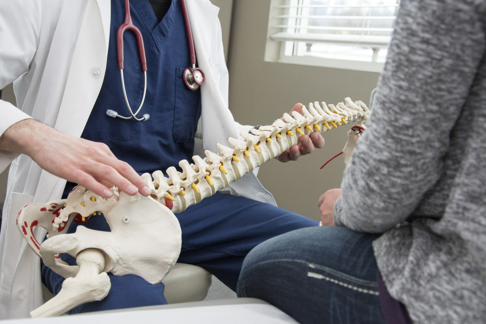 doctor explaining spinal procedure to patient using a spine model
