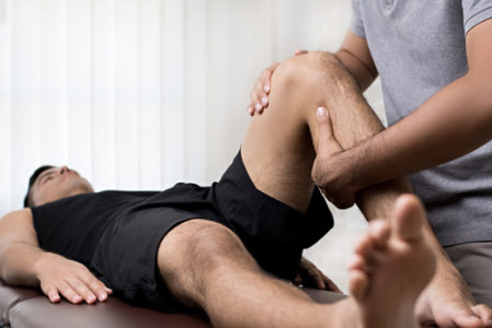 therapist helping man with knee exercise